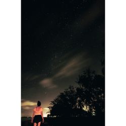 Rear view of silhouette person against sky at night