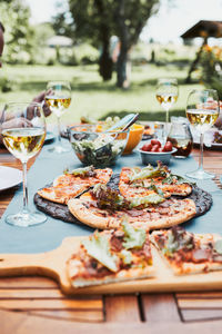 Dinner in a home garden. pizza, salads, fruits and white wine on table in a orchard in a backyard