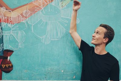 Young woman looking away while standing against wall