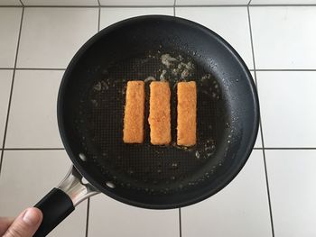 High angle view of person holding food in pan over floor