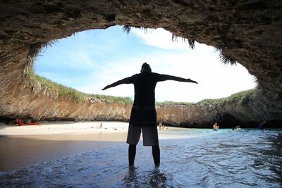 Rear view of man standing on rock at beach