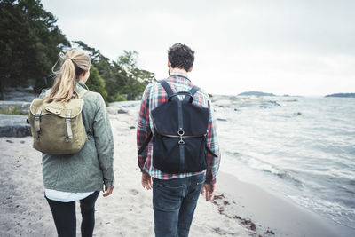 Rear view of wonderlust couple walking together on beach