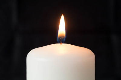 Close-up of lit candle in darkroom