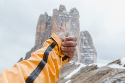Close-up of man holding rock against sky during winter