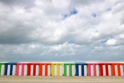 Multi colored huts on beach against sky