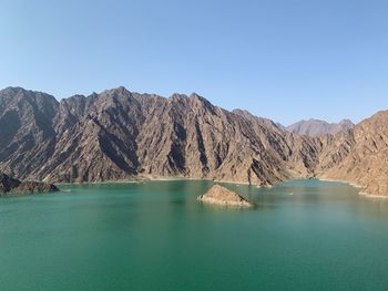 Scenic view of lake and mountains against clear blue sky