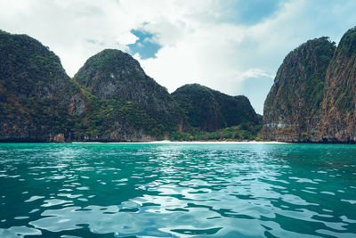 Scenic view of sea by mountain against sky