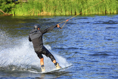 Full length of man splashing water while kiteboarding in sea