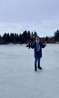 Full length of boy standing on snow covered field against sky