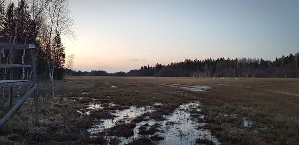 Scenic view of snowy field against clear sky during sunset