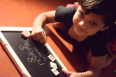 Portrait of girl writing on slate while kneeling on floor at home