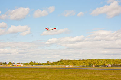 Airplane flying over field against sky