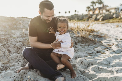 Close up of father holding young toddler girl at beach