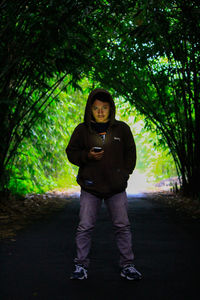 Portrait of young man standing against trees