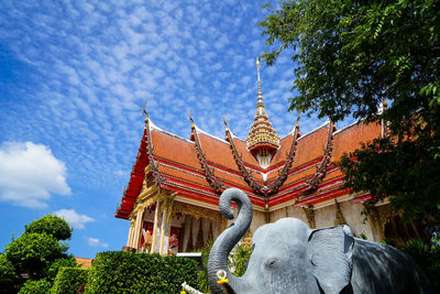 Low angle view of statue by building against sky