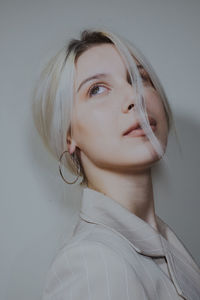 Close-up of young woman wearing blazer against wall