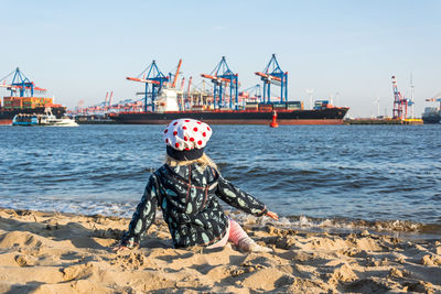 Rear view of boy sitting on beach