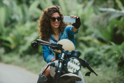 Woman taking selfie while sitting on motor cycle