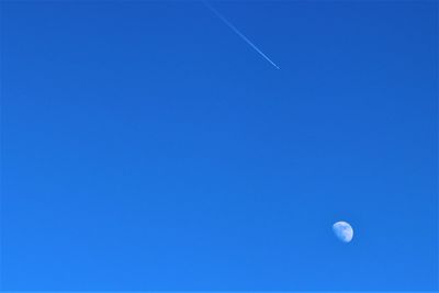 Low angle view of moon against clear blue sky