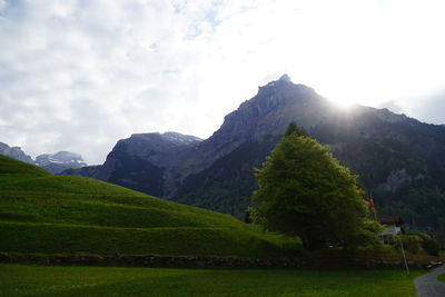 Scenic view of green landscape and mountains against sky