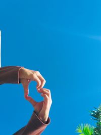 Cropped hand gesturing against blue background