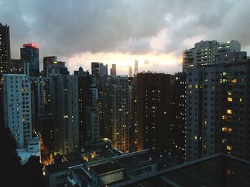 Illuminated buildings in city against sky at sunset