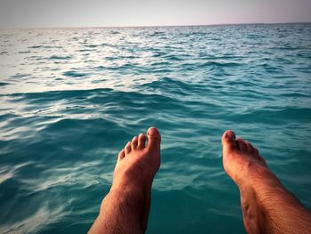 Low section of man by sea against sky