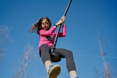 Girl on a children's zip line with a blue sky background