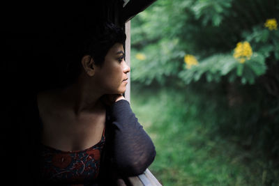 Thoughtful woman looking through window while traveling in train