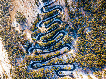 Aerial view of winding road amidst snow covered trees in forest
