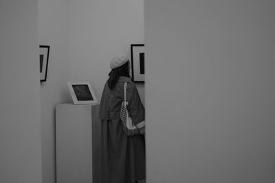 Side view of woman standing against wall