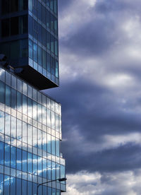 Low angle view of modern building against cloudy sky