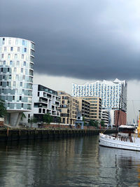 Buildings by river against sky in city