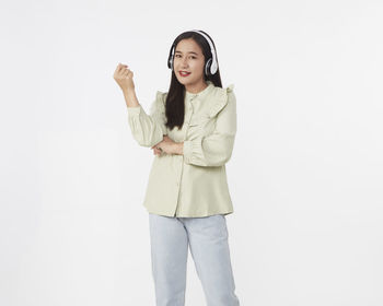 Portrait of smiling young woman standing against white background