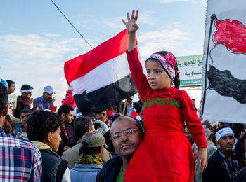 Group of people looking at flag against sky