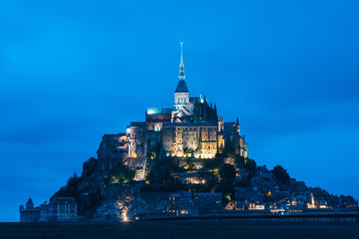 Illuminated building against blue sky at night
