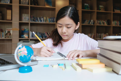 Girl writing while sitting in library