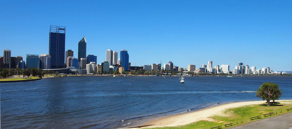 City at waterfront against blue sky