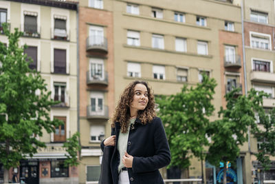 Full length of woman standing against building in city