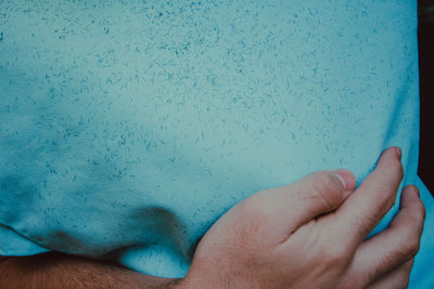 Close-up of hands against blue wall