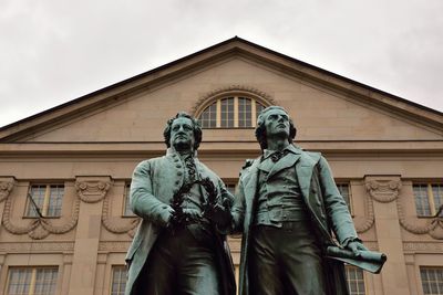 Low angle view of statue against historic building against sky