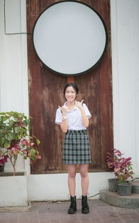Portrait of smiling girl standing against door