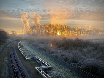 Railroad tracks against sky during sunset