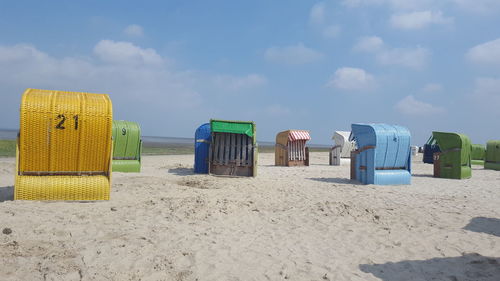 Hooded chairs on beach against sky