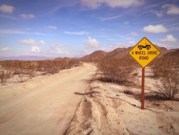 Road sign on mountain against sky