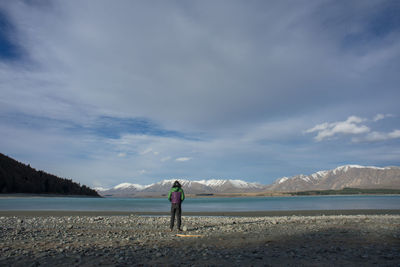 Rear view of man standing on mountain against sky