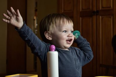 Close-up of boy holding pacifier against door at home