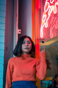 Portrait of young woman standing against door