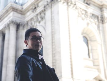 Low angle portrait of young man standing against st paul cathedral
