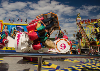 People enjoying amusement park ride against sky